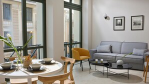 Un salon moderne avec une table de salle à manger ronde, des chaises en bois, un canapé gris et une table basse.