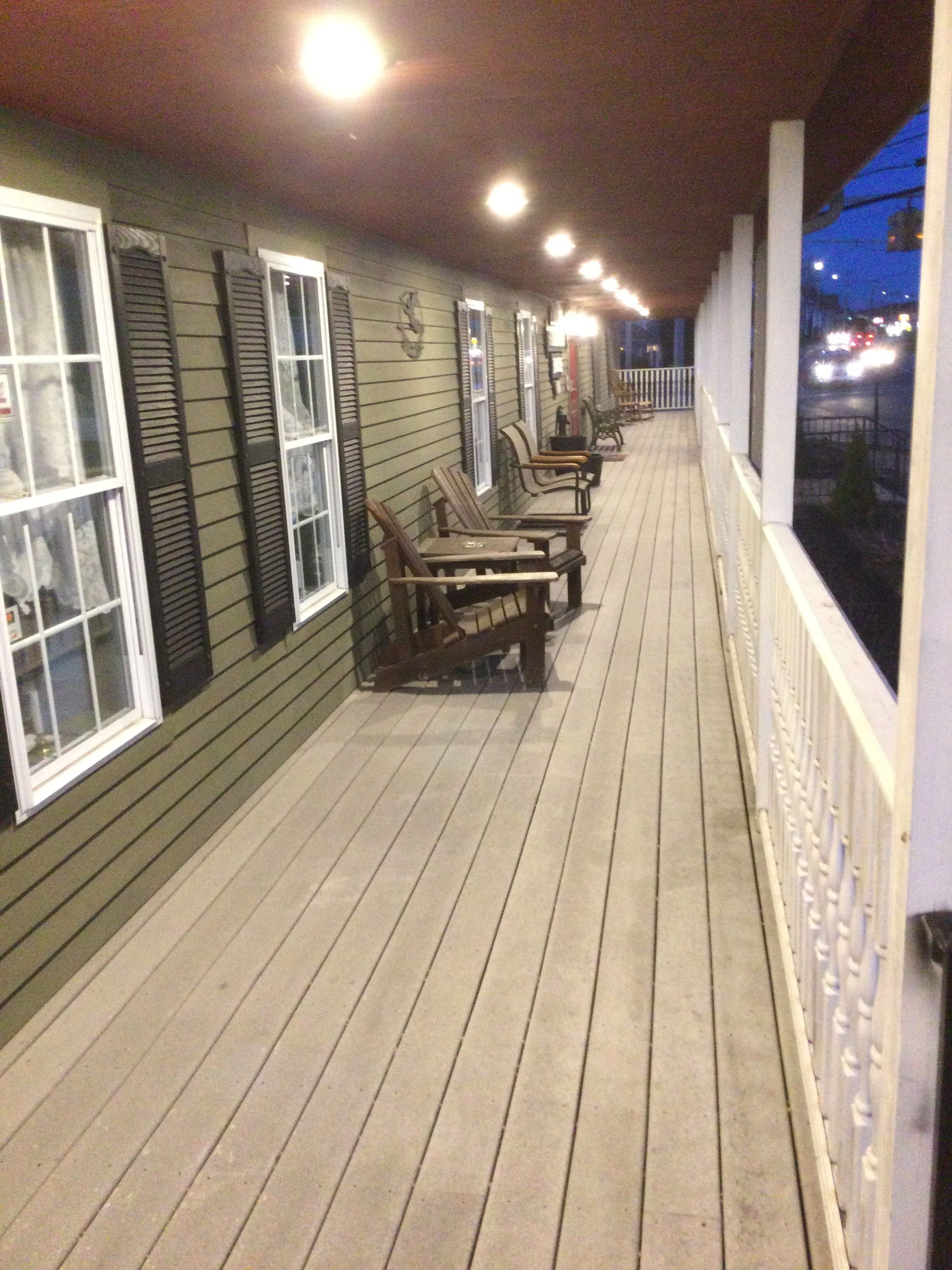 Um deck de madeira com assentos externos e vista para a rua à noite.