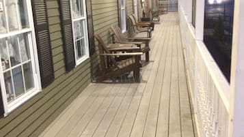 Um deck de madeira com assentos externos e vista para a rua à noite.