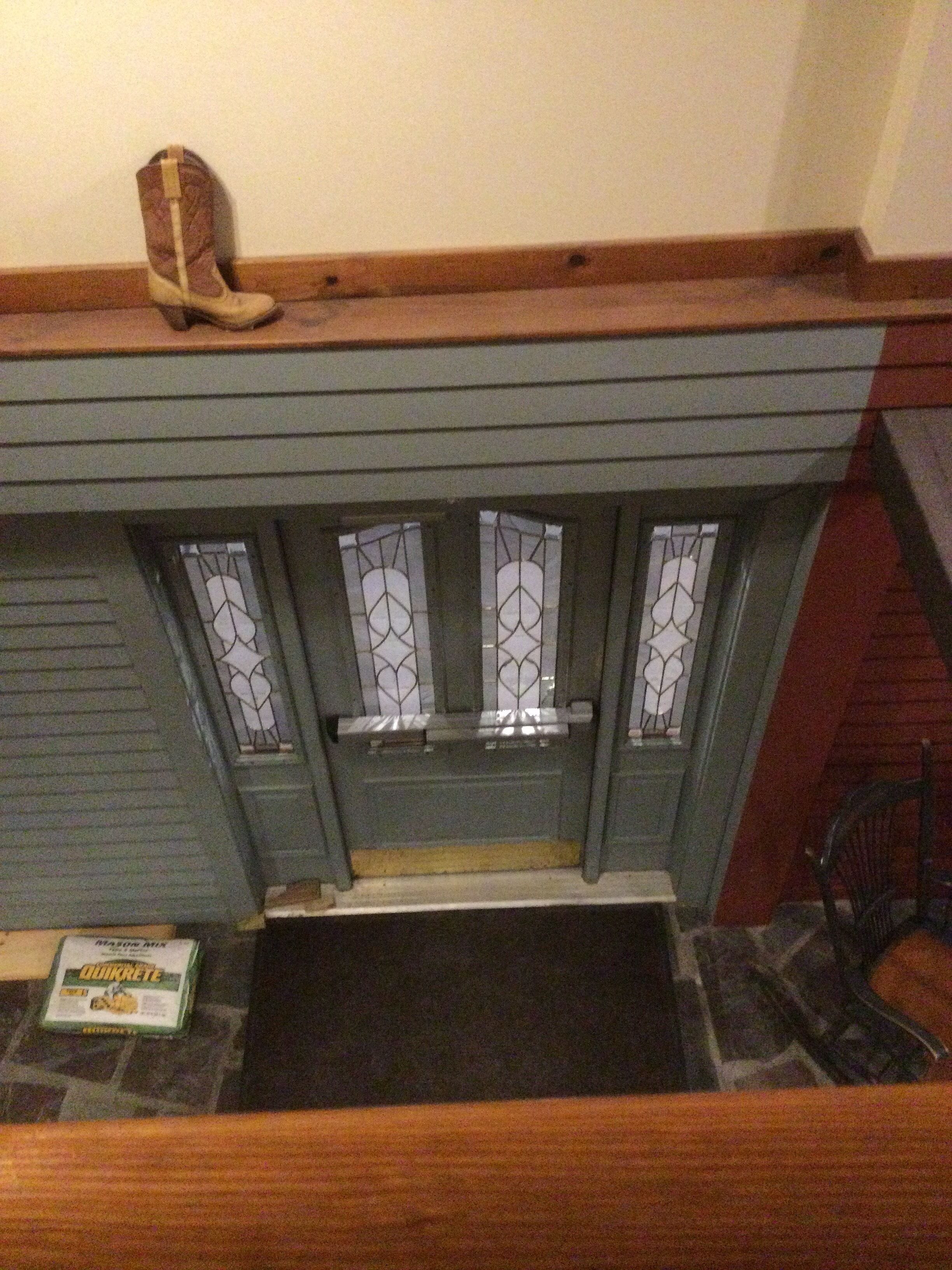 A fireplace with a wooden mantel, stained glass windows, and a pair of boots on top.