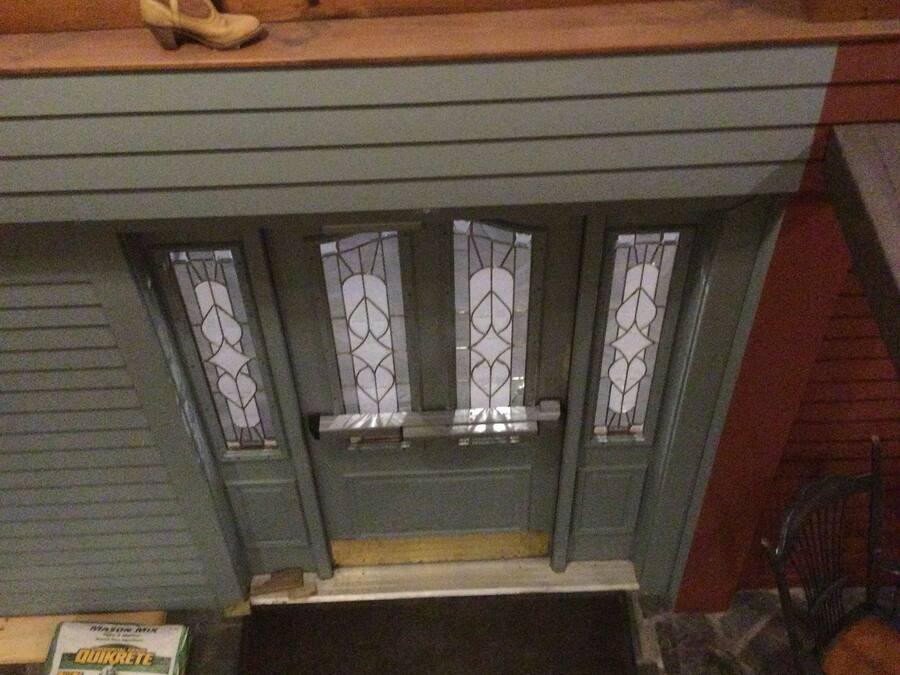 A fireplace with a wooden mantel, stained glass windows, and a pair of boots on top.