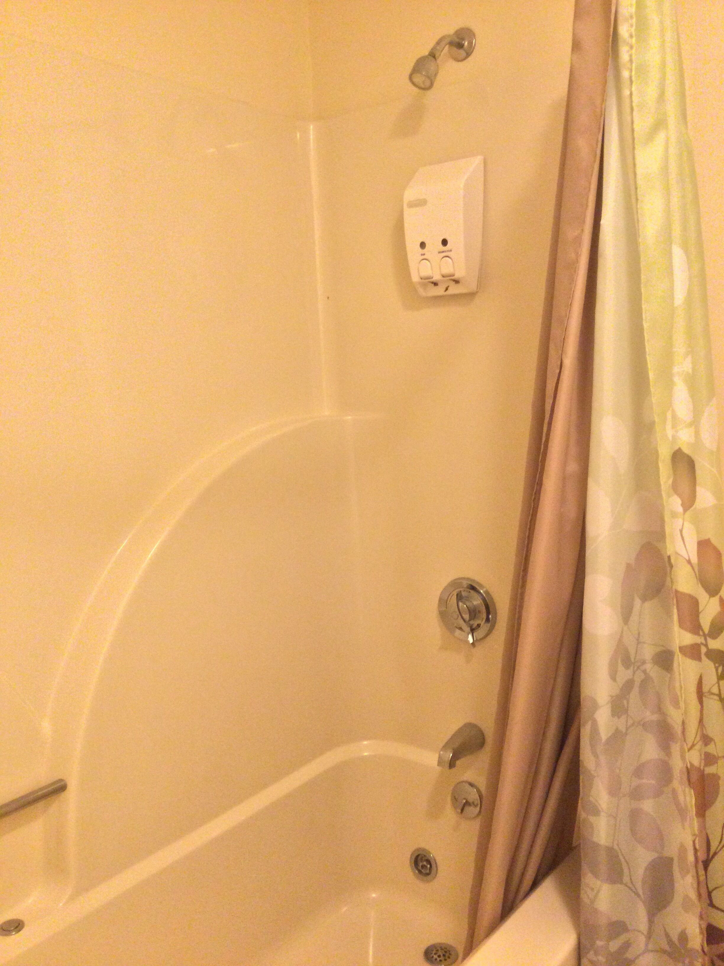 A bathtub with a showerhead, a faucet, and a control knob.