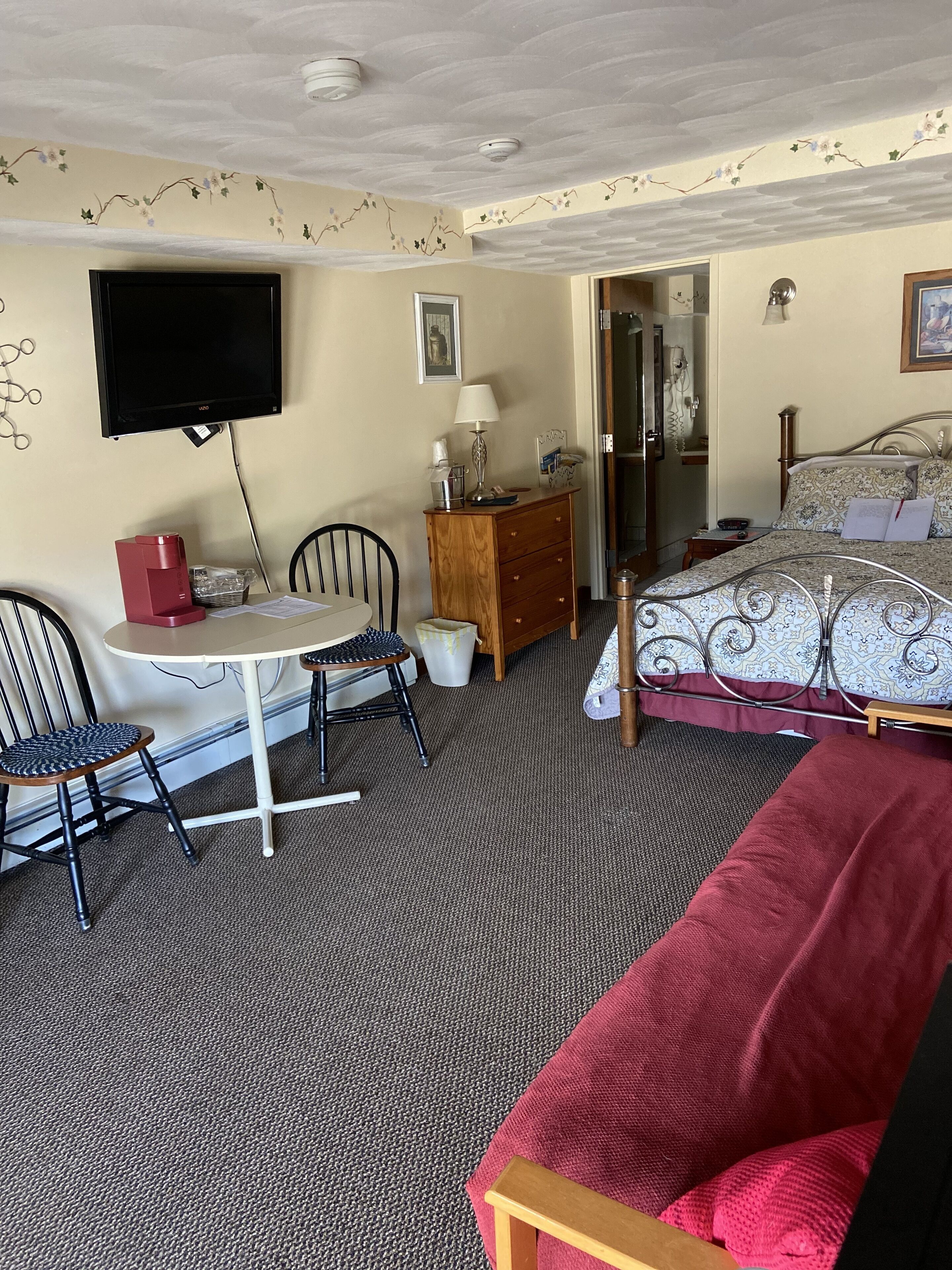 Ein Zimmer mit einem Bett, einem Schreibtisch mit Stuhl, einem Fernseher und einer Kommode.