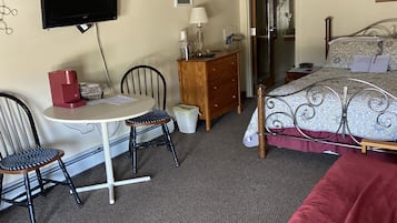 Ein Zimmer mit einem Bett, einem Schreibtisch mit Stuhl, einem Fernseher und einer Kommode.