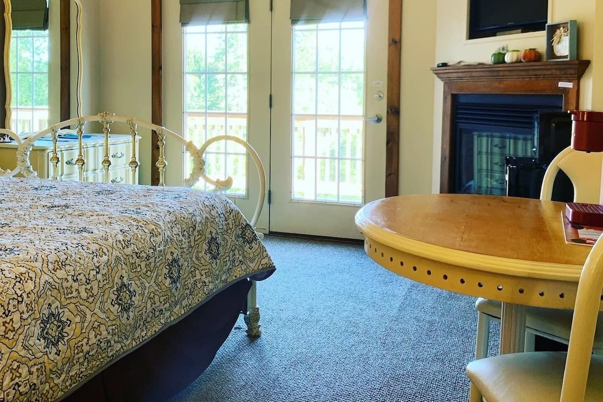 A bedroom with a bed, a chair, a fireplace, and a television.