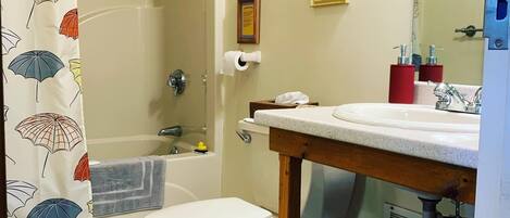 A bathroom with a toilet, sink, shower, and a towel rack.
