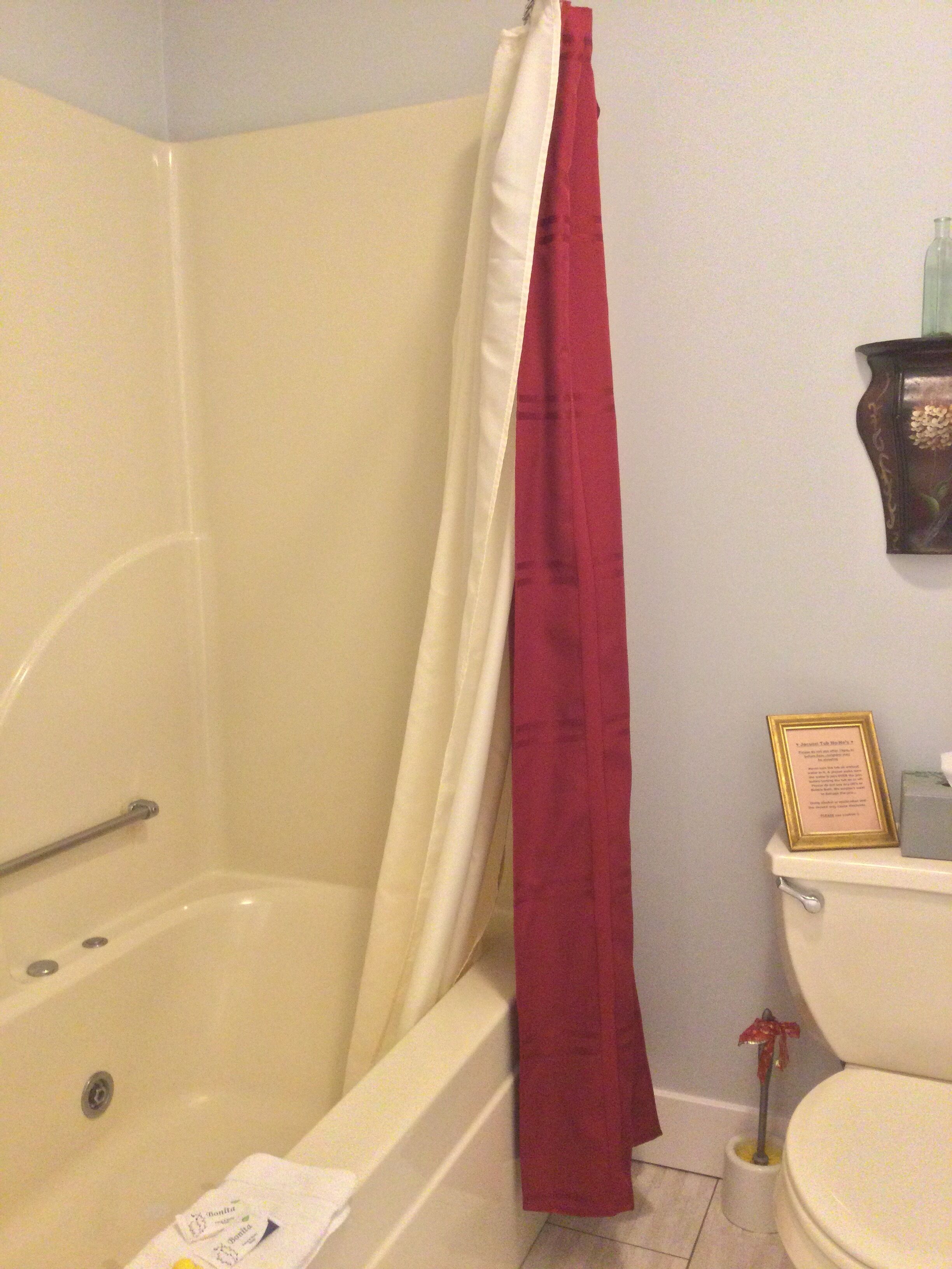 Ein Badezimmer mit Badewanne, Toilette und einem gerahmten Zertifikat an der Wand.