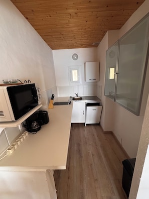 A compact kitchen with a microwave, coffee maker, and a sink.