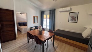 Un espacio habitable compacto con una mesa de comedor, un sofá, una cama y un ventilador de techo.