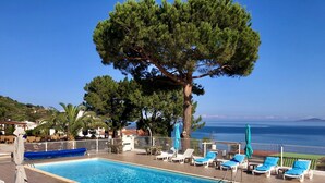 Zona de piscina con sillones de descanso y vista al mar.