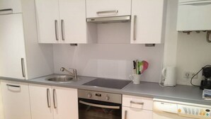 A compact kitchen with a dishwasher, oven, sink, and a built-in washing machine. - Modern, quiet apartment in an old building (Wien)