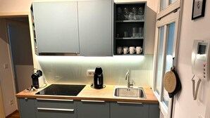Et moderne køkken med lysegrå skabe, en sort induktionskogetop, en vask og en kaffemaskine.