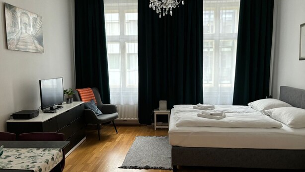 Et moderne hotelværelse med seng, skrivebord med computer, stol og fjernsyn.