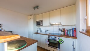 A compact kitchen with white cabinets, a microwave, a stove, and a sink. - Chalet Asphodel (Haute-Nendaz)