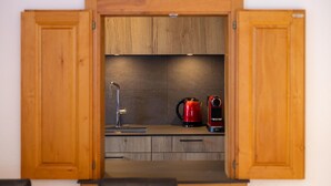 A kitchen with wooden cabinets, a sink, and a red kettle. - Ecluses 15 - close to ski lift & centre - Nendaz (Haute-Nendaz)