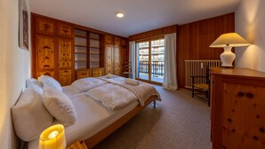 A bedroom with a large bed, wooden paneling, a window with a view, a radiator, and a lamp. - Ecluses 15 - close to ski lift & centre - Nendaz (Haute-Nendaz)