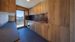 A modern kitchen with wooden cabinets, a black countertop, and a built-in oven. - Ecluses 15 - close to ski lift & centre - Nendaz (Haute-Nendaz)