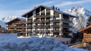 A multi-story hotel with balconies, a ski slope in the background, and snow-covered mountains. - Ecluses 15 - close to ski lift & centre - Nendaz (Haute-Nendaz)