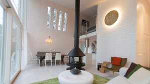 Uma sala de estar moderna com lareira, um espaço de jantar e uma escada para um andar superior.