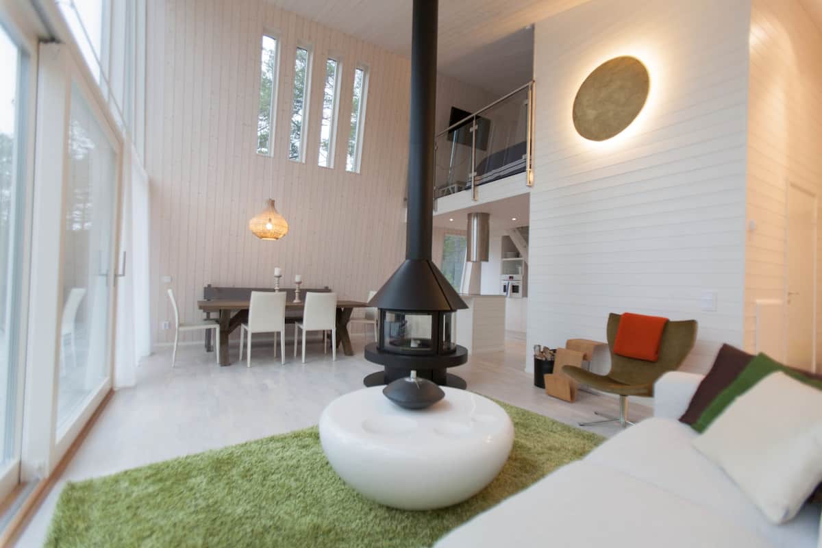 Ein modernes Wohnzimmer mit Kamin, Essbereich und einer Treppe zu einer oberen Etage.