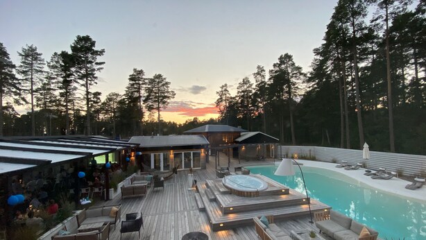 Um deck de madeira com área de estar externa, banheira de hidromassagem e piscina.