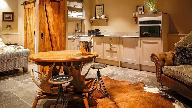 Un salón acogedor con una mesa redonda de madera, un sofá y una zona de comedor con una silla de madera.