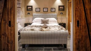 Un dormitorio con una cama grande, un tapete mullido y cuadros enmarcados en la pared.