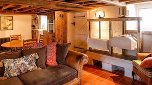 Ein rustikales Interieur mit Ledersofa, Holzesstisch und Steinofen.