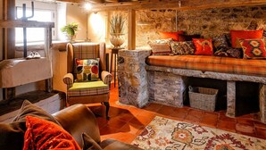 Ein gemütliches Wohnzimmer mit Kamin aus Stein, einer bequemen Couch und einem Ledersessel.
