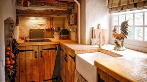 Eine rustikale Küche mit Holzschränken, einem Spülbecken und einem Fenster mit einem Hahn-Dekor.