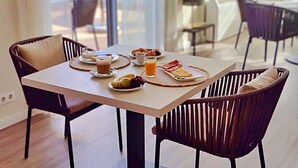 Une table à manger dressée avec des aliments pour le petit-déjeuner, notamment des œufs, des toasts et des fruits, dans une pièce lumineuse et meublée dans un style moderne.