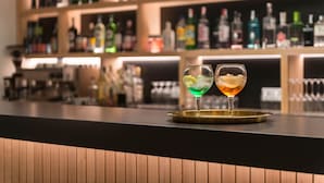 Un comptoir de bar avec deux verres de cocktails, un plateau et, en arrière-plan, des étagères remplies de bouteilles de spiritueux.