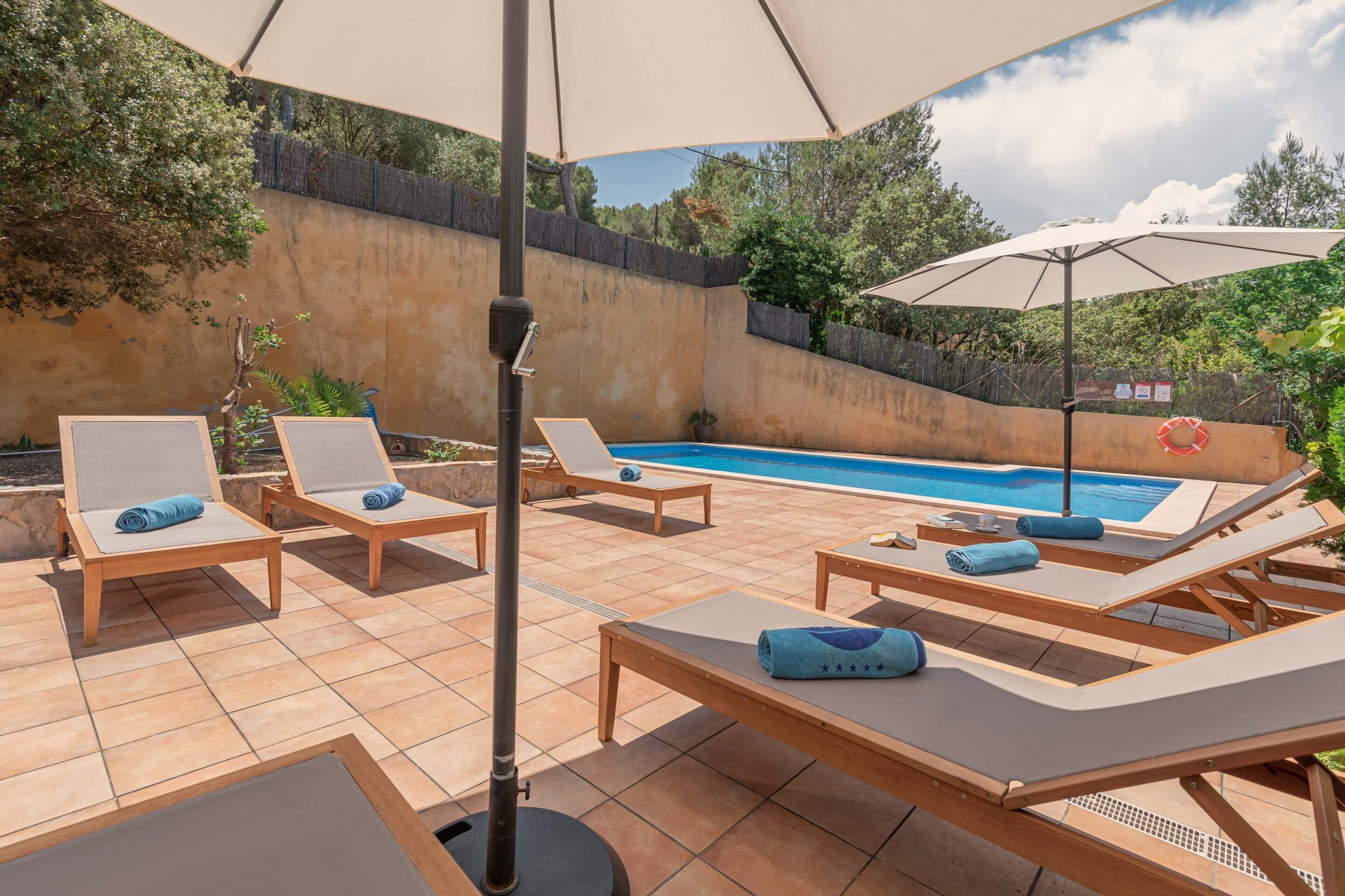 A poolside area with lounge chairs, umbrellas, and a swimming pool.