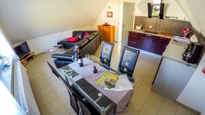 A compact living space with a dining area, a sofa, a kitchen, and a small TV.