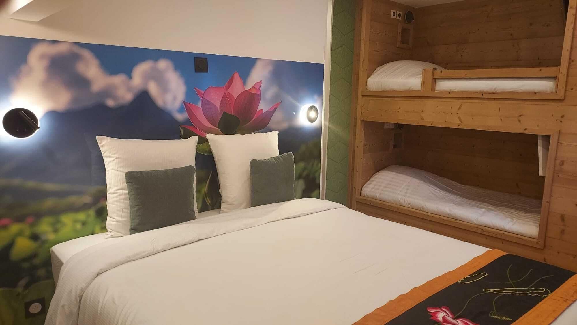 Une chambre avec un lit superposé, un lit avec des oreillers et une fresque représentant une fleur de lotus.