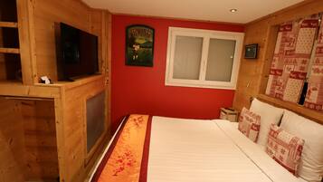 Habitación con paneles de madera, una cama, un televisor, una ventana y un tapiz acolchado.