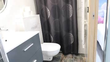 Een badkamer met toilet, wastafel met spiegel en douchegordijn met een geometrisch patroon.