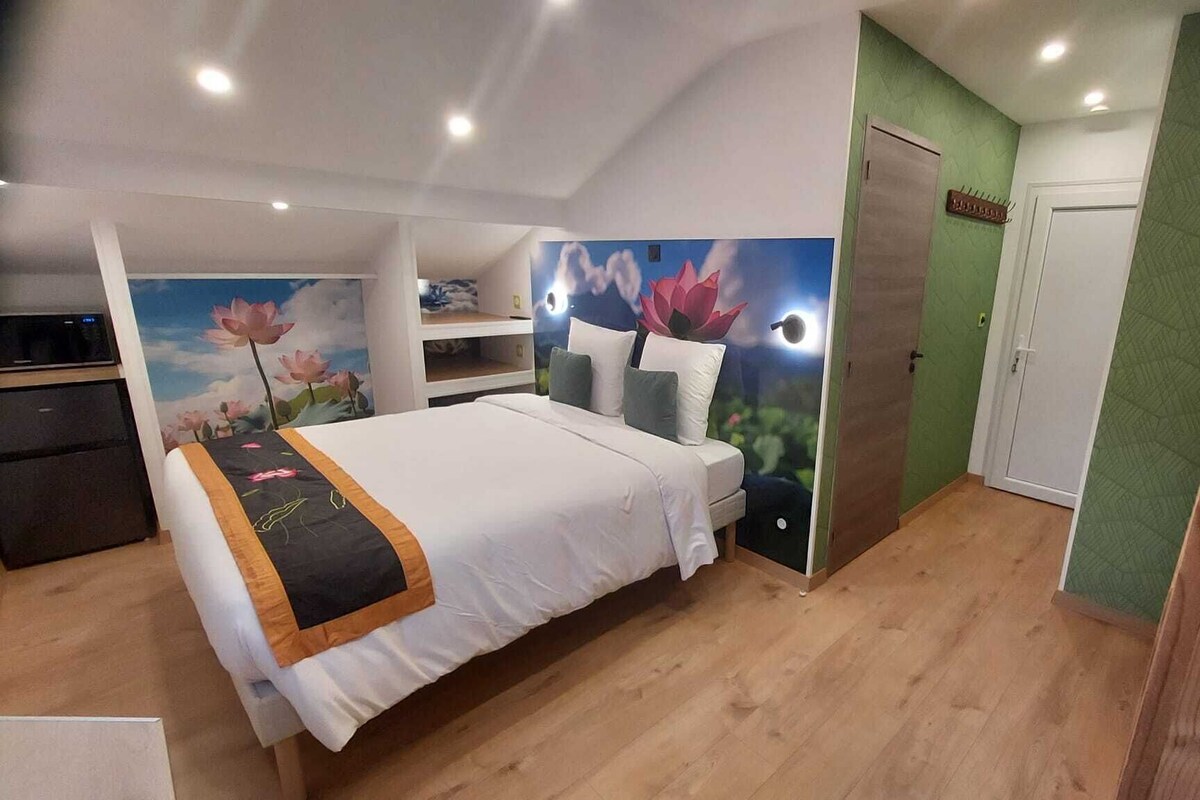 A bedroom with a bed, a small desk, a wardrobe, and a green wall.