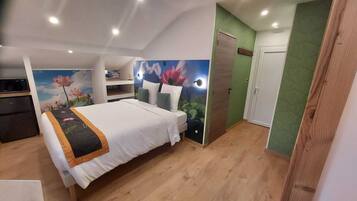 Un dormitorio con cama, un escritorio pequeño, un armario y una pared verde.