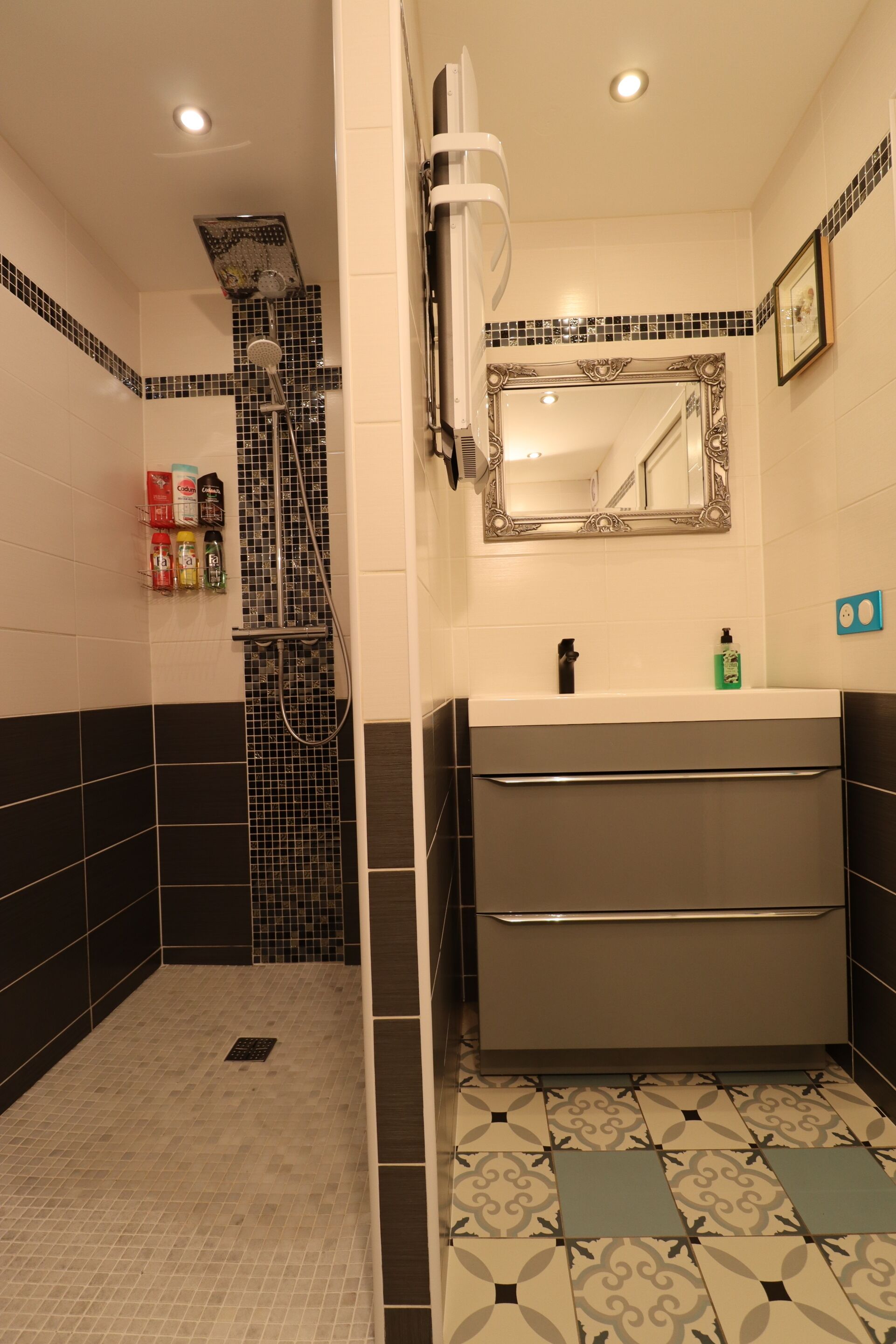 Une salle de bain avec une douche, un lavabo et un miroir.