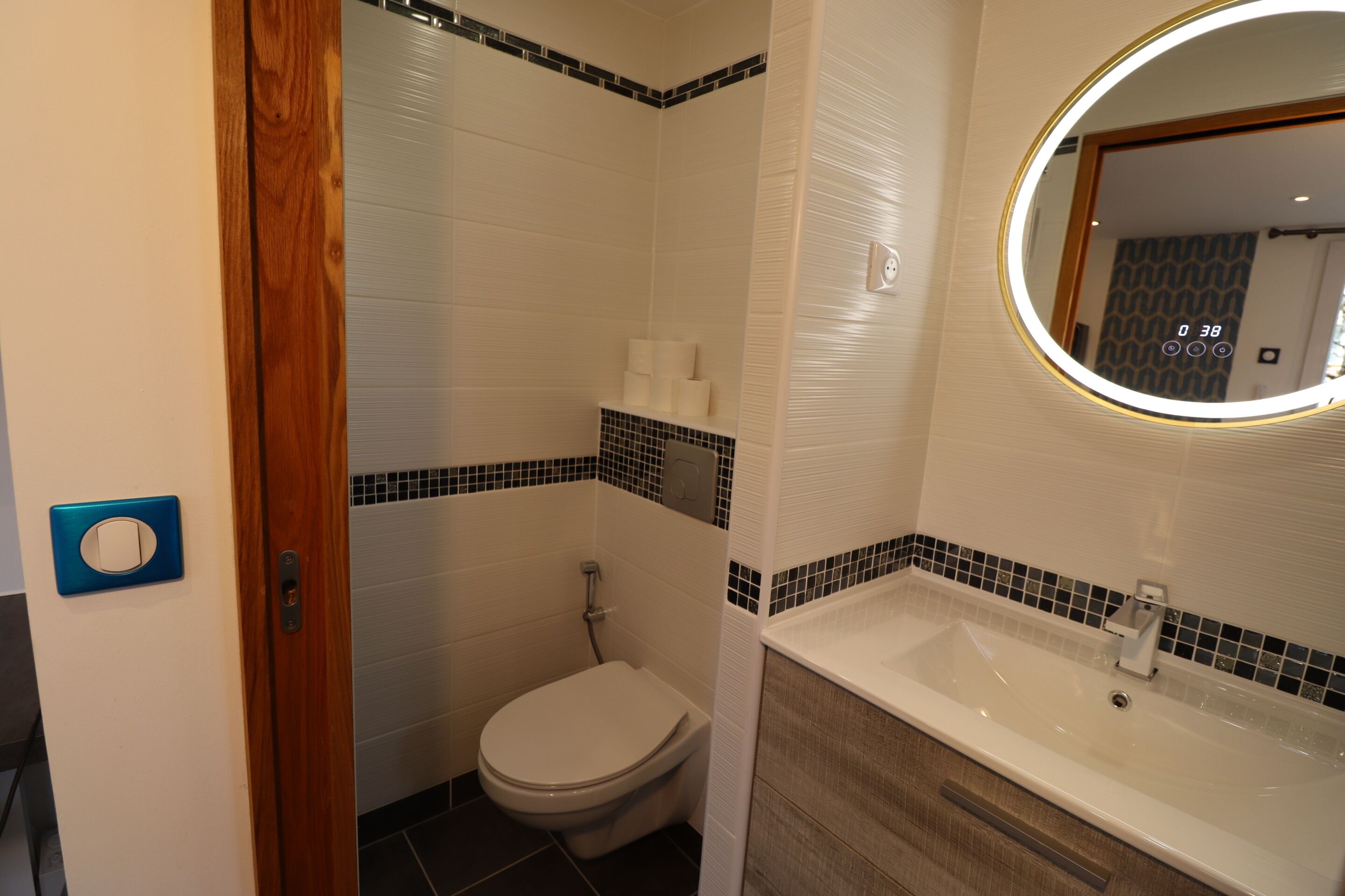 A bathroom with a toilet, sink, and mirror.