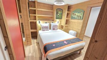 Une pièce en bois avec un lit, des étagères et un luminaire fixé au mur.