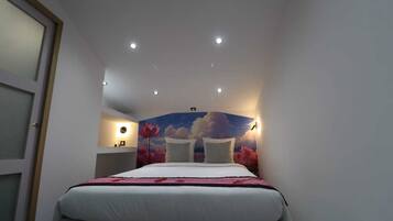 A bedroom with a bed, a nightstand, a wall-mounted lamp, and a ceiling light.