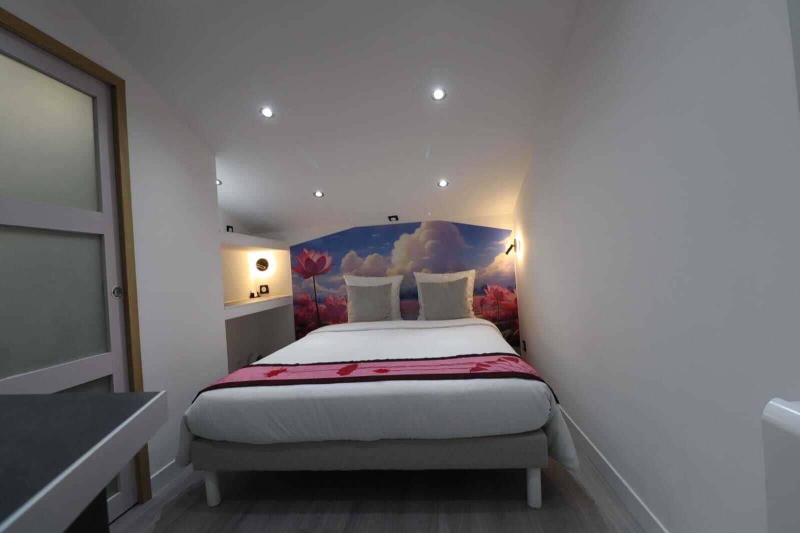 Un dormitorio con cama, mesita de noche, lámpara de pared y luz de techo.