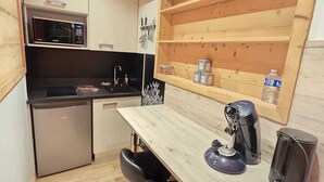 A compact kitchen with a microwave, sink, and a coffee maker on the counter. - Le Lotus Blanc (Albertville)