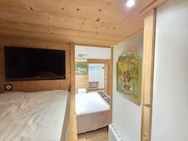 Une pièce en bois avec un lit, un téléviseur et un tableau accroché au mur.