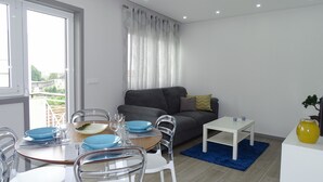 A modern living room with a dining area, grey sofa, and a small white table. - Rs porto Apartments (Porto)