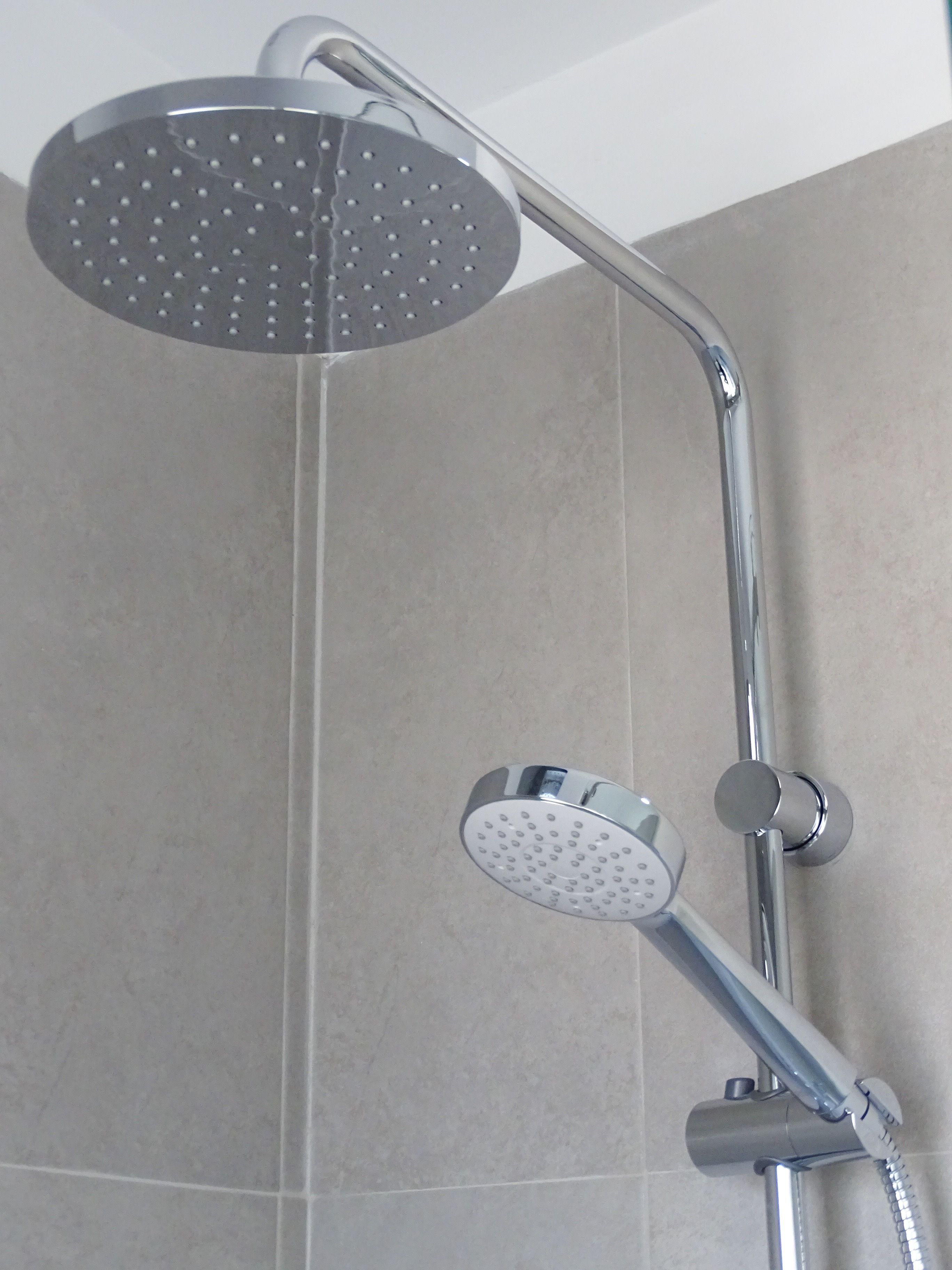 A shower with a round head and a handheld attachment.