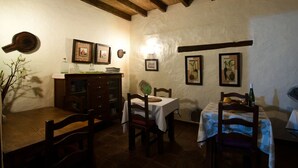 Ein rustikaler Essbereich mit Holztisch und -möbeln, einem mit weißer Tischdecke bedeckten Tisch und gerahmten Kunstwerken an den Wänden.