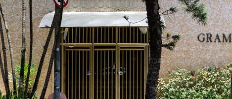 A building entrance with a tiled wall, a metal gate, and a sign indicating no parking.